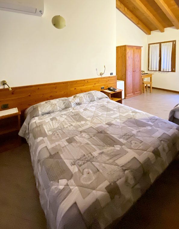 Un’altra camera, con il letto matrimoniale, l’armadio in legno e il soffitto a travi