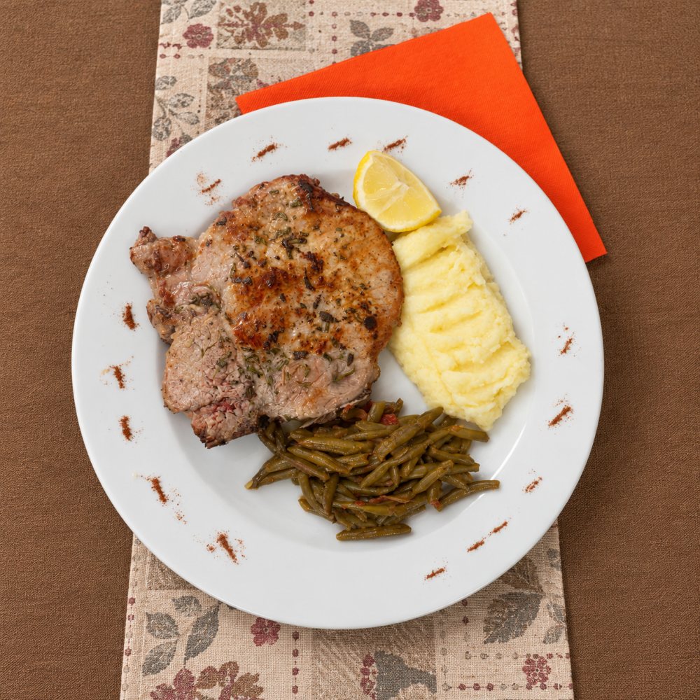 Una braciola alle erbe con purè di patate, fagiolini e uno spicchio di limone