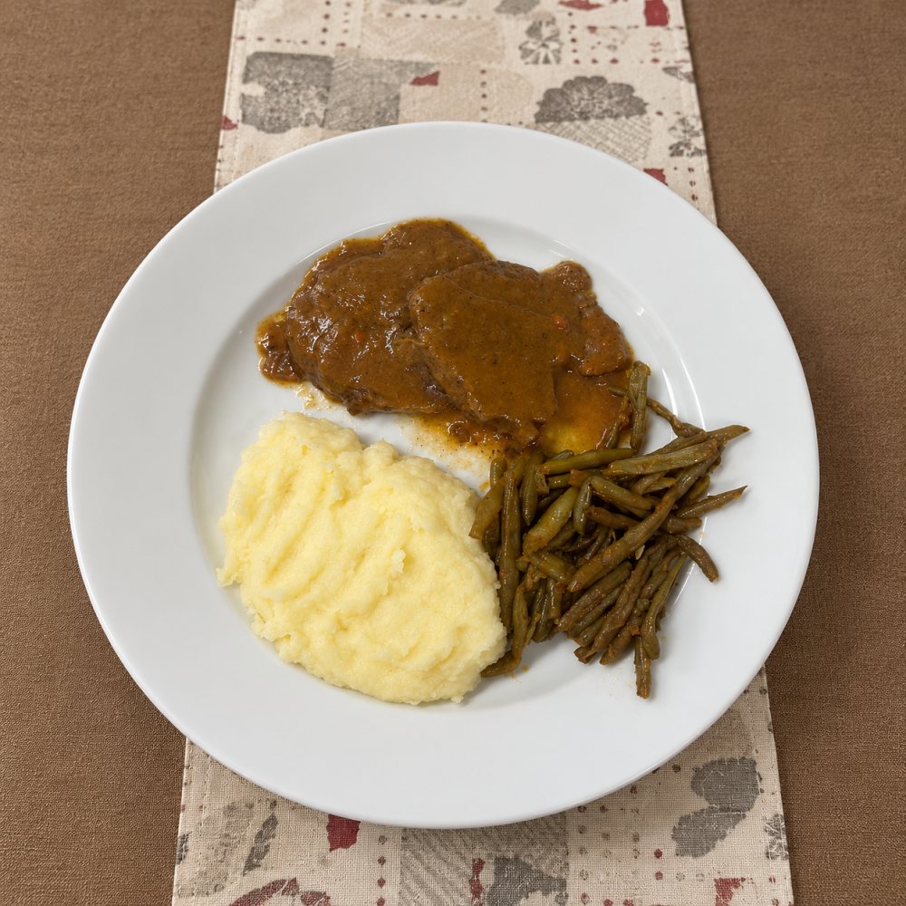 Un piatto di carne in umido con purè di patate e fagiolini