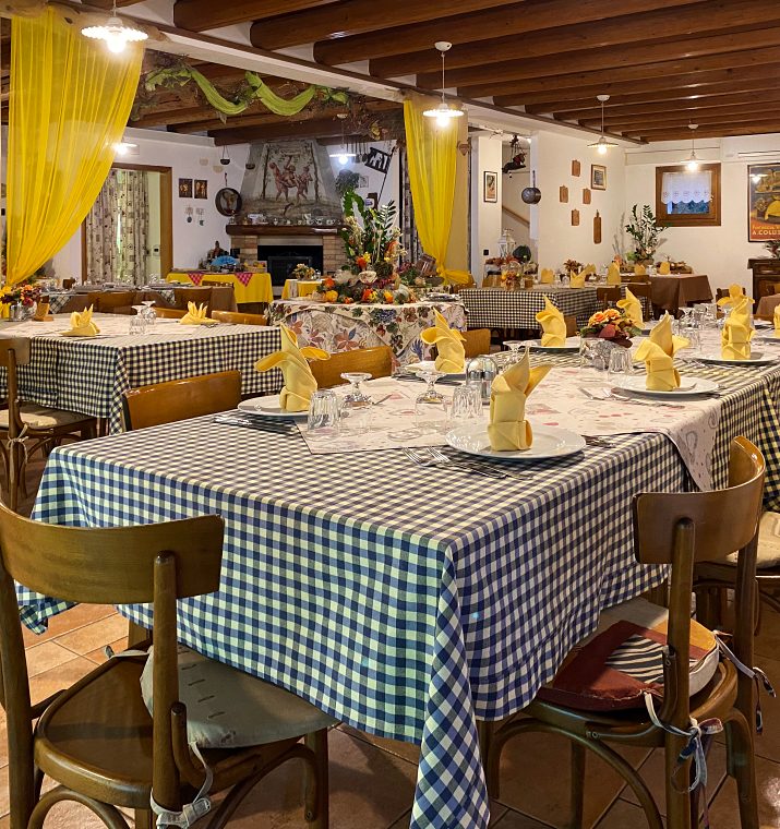 La sala del ristorante con le tovaglie a quadretti e il camino in fondo
